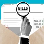 Man examining a bill with a magnifying glass, reviewing a debt claim as part of debt remediation