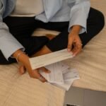 Person reviewing papers beside a laptop while preparing a debt validation letter